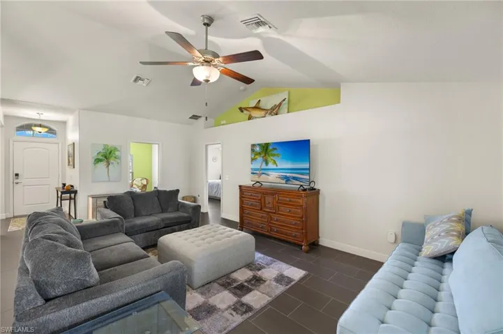 Living area with ceiling fan, vaulted ceiling, and baseboards