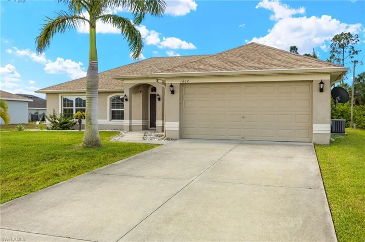 Single story home featuring stucco siding, central AC unit, concrete driveway, a front yard, and a garage
