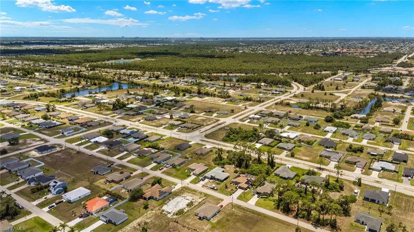 Aerial view of property and surrounding area featuring nearby suburban area and a large body of water