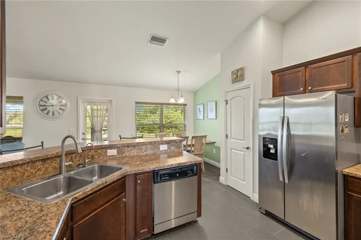 Kitchen featuring appliances with stainless steel finishes, a sink, vaulted ceiling, a chandelier, and pendant lighting