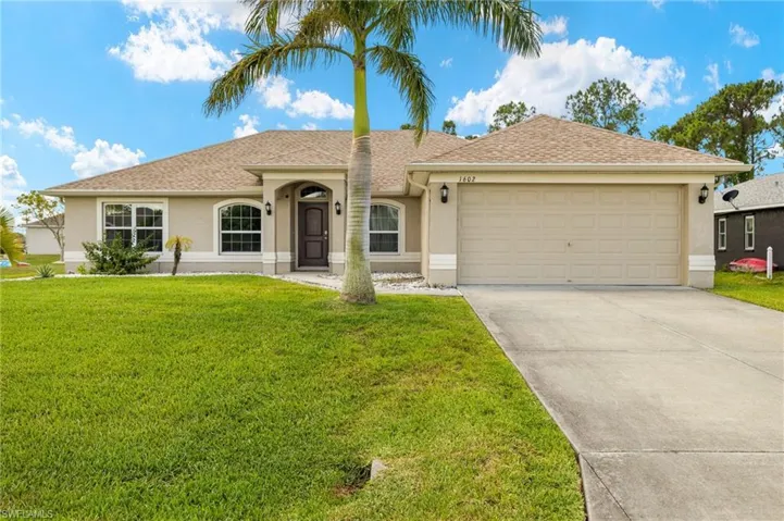 View of front of house featuring stucco siding, a garage, driveway, and a front yard