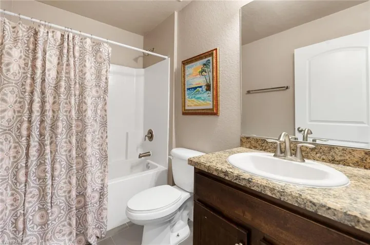 Full bath featuring toilet, vanity, tile patterned flooring, and shower / tub combo with curtain