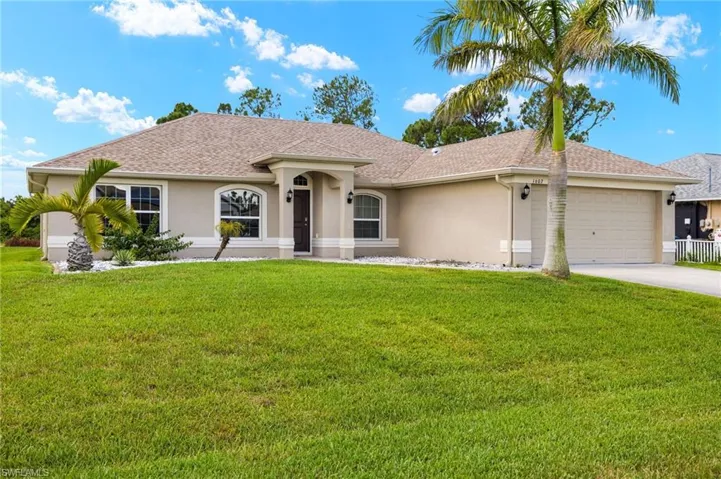 Ranch-style home with stucco siding, a front yard, an attached garage, driveway, and a shingled roof