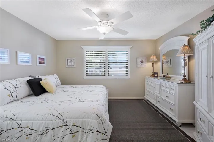 Bedroom with a textured ceiling, baseboards, and a ceiling fan
