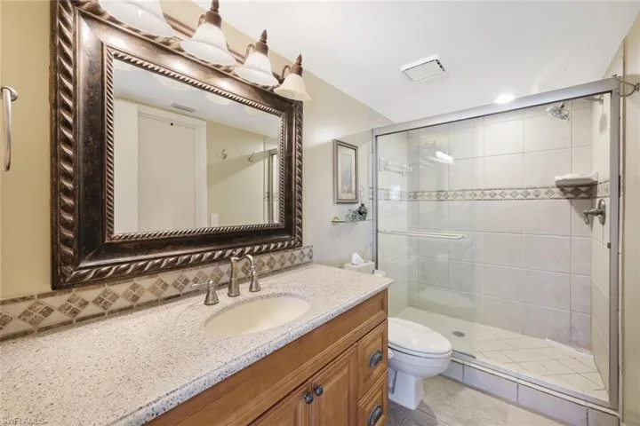Bathroom featuring tasteful backsplash, vanity, a stall shower, and toilet