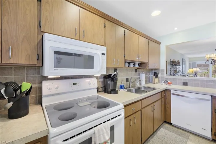 Kitchen with white appliances, light countertops, a sink, and decorative backsplash