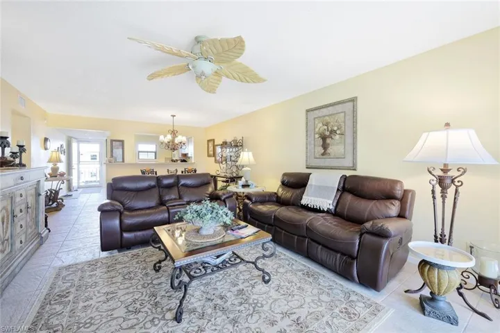Living room featuring light tile patterned floors, visible vents, and ceiling fan with notable chandelier