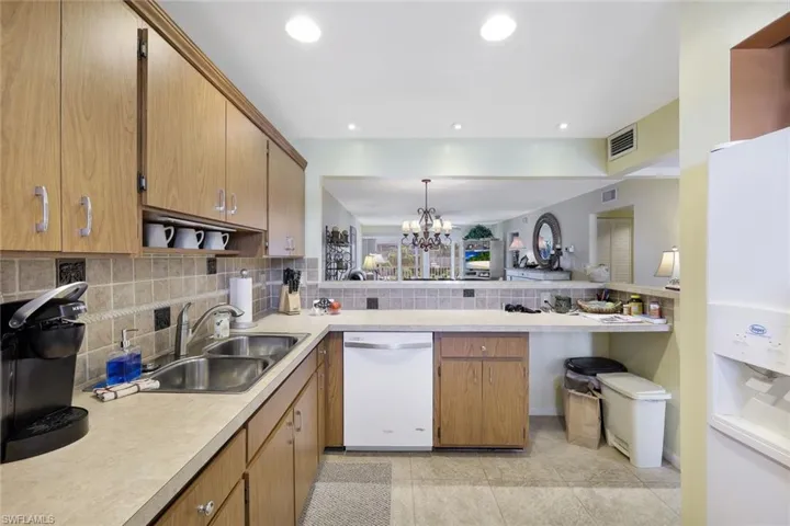 Kitchen featuring visible vents, light countertops, a sink, white dishwasher, and open floor plan