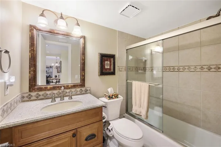Full bathroom with toilet, vanity, visible vents, and bath / shower combo with glass door