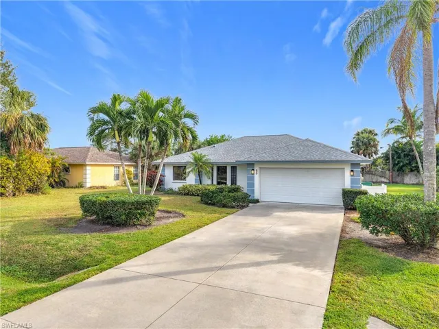 Single story home featuring an attached garage, driveway, a front yard, a shingled roof, and stucco siding