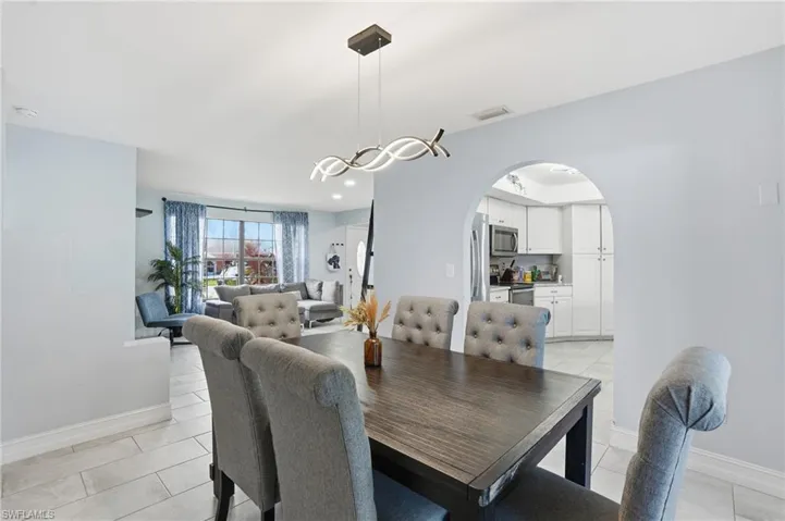 Dining area featuring arched walkways and light tile patterned flooring