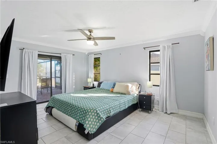 Bedroom with access to outside, ornamental molding, ceiling fan, and light tile patterned flooring