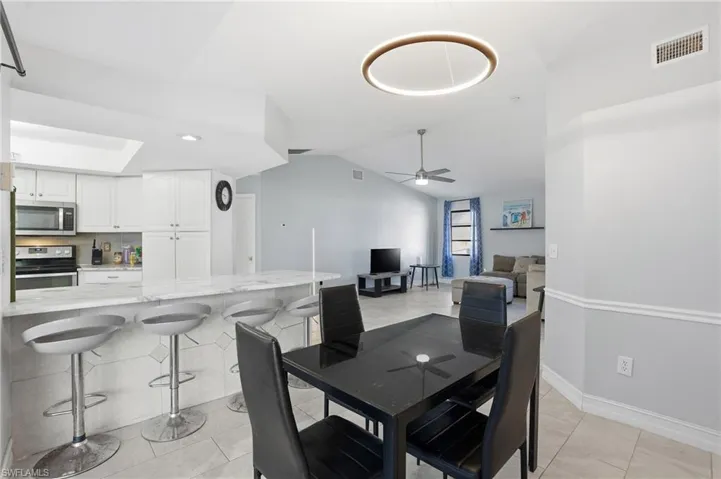 Dining room with vaulted ceiling, a ceiling fan, and light tile patterned floors