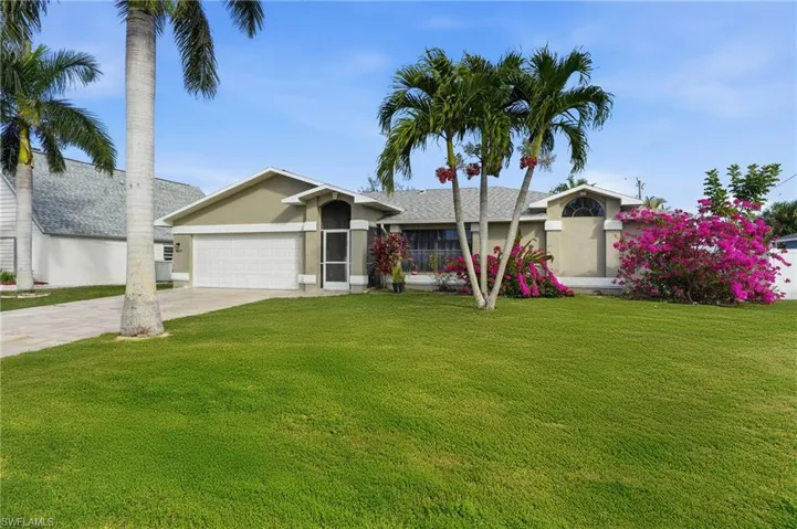 View of front of home with a front yard, driveway, a garage, and stucco siding