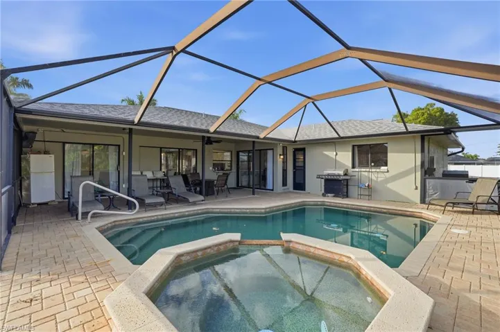 View of pool with a sunroom, glass enclosure, a patio, a pool with connected hot tub, and grilling area