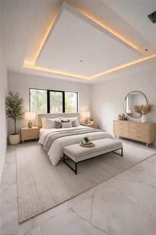 Bedroom featuring a tray ceiling and light marble finish floors