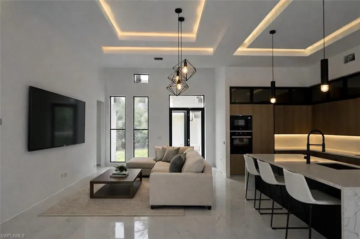 Living room with a tray ceiling and light marble finish flooring