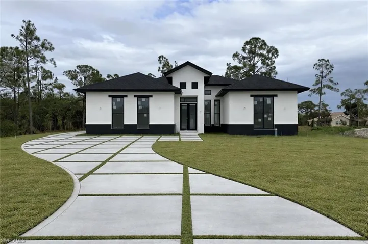 Rear view of house featuring stucco siding, a lawn, and concrete driveway