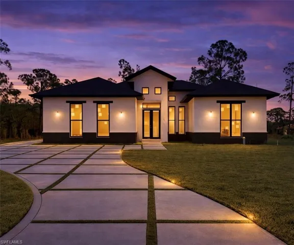 View of front of house featuring a yard, stucco siding, and concrete driveway
