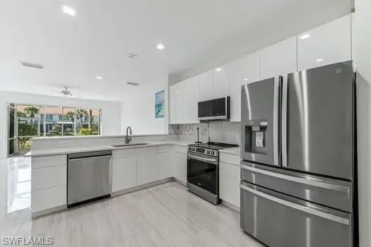Kitchen featuring appliances with stainless steel finishes, modern cabinets, white cabinetry, light countertops, and recessed lighting