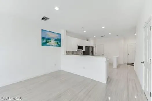 Dining room with light wood finished floors and recessed lighting