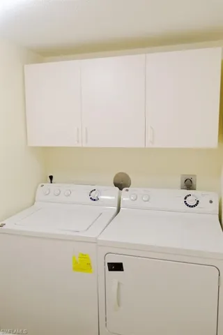 Clothes washing area with cabinets and separate washer and dryer