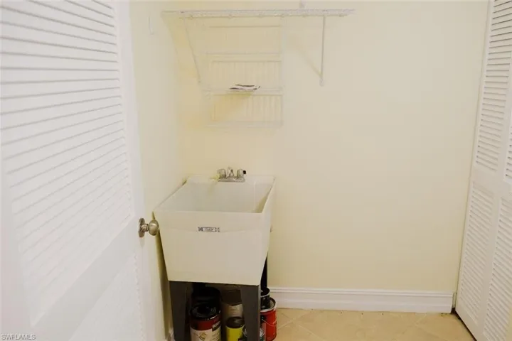 Clothes washing area with sink and light tile patterned floors