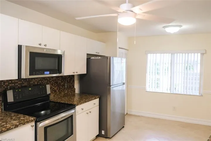 Kitchen with ceiling fan, decorative backsplash, stainless steel appliances, and white cabinets