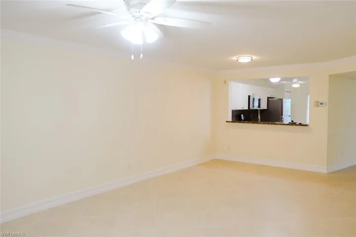 Tiled empty room with ceiling fan and ornamental molding