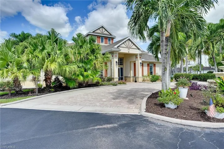 Architectural exterior featuring a multi-gabled roofline, lap siding, decorative timber accents, paver driveway, and mature palm tree landscaping
