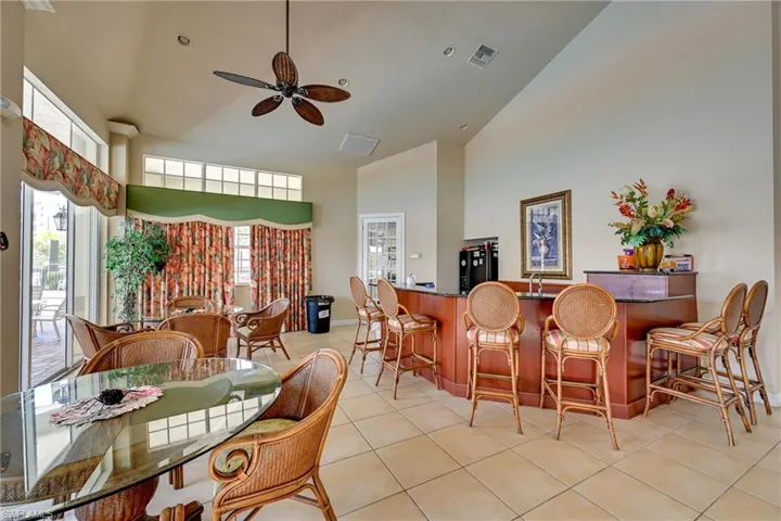 Vaulted ceilings, built-in wet bar with stone countertop, tile flooring, and large picture windows
