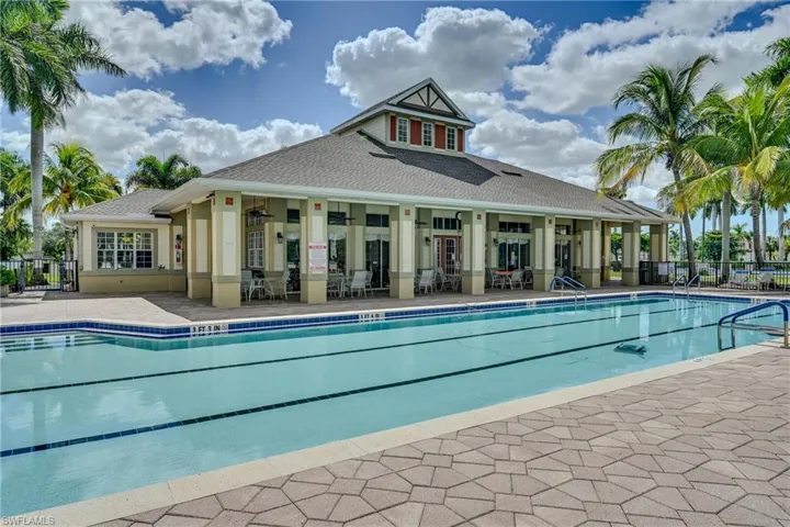 In-ground lap pool featuring a multi-lane design, paved sun deck, covered loggia, and shingled roof exterior