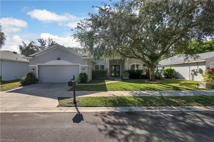 View of front of property featuring a front lawn, stucco siding, concrete driveway, and an attached garage