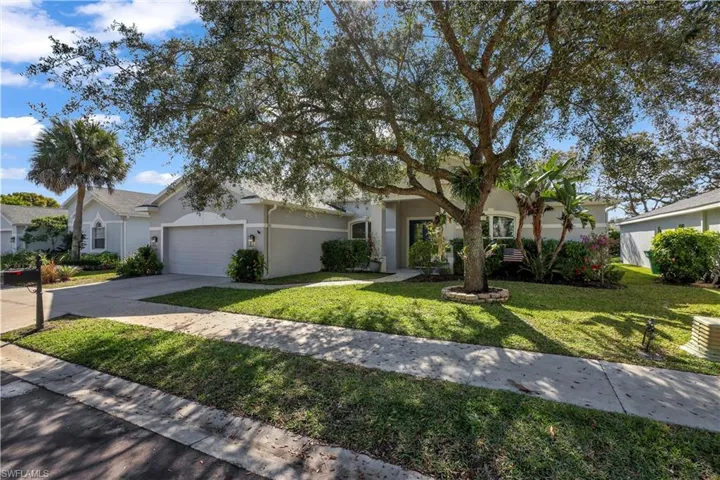 View of front of house with stucco siding, a front yard, driveway, and an attached garage