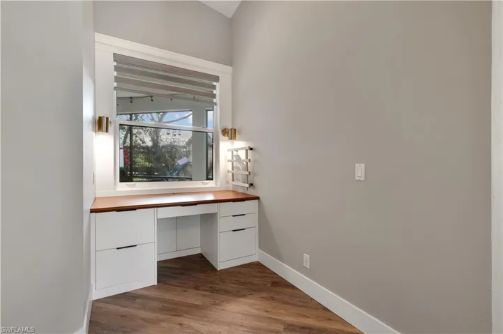 Unfurnished office with built in desk and dark wood-type flooring