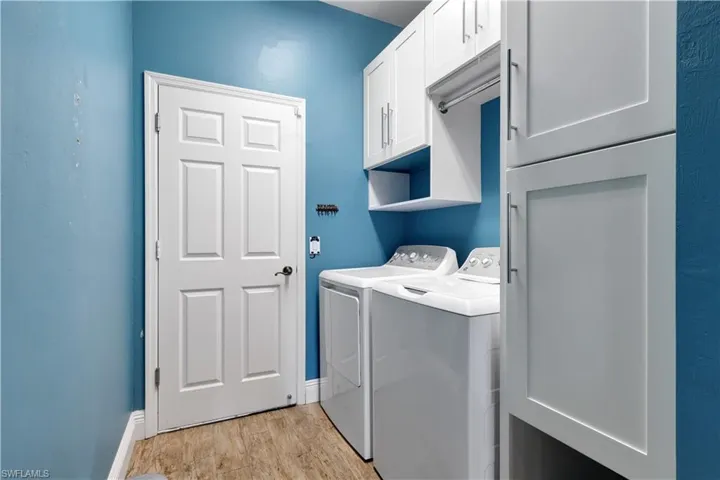 Laundry area featuring cabinet space, light wood-style floors, and washing machine and clothes dryer