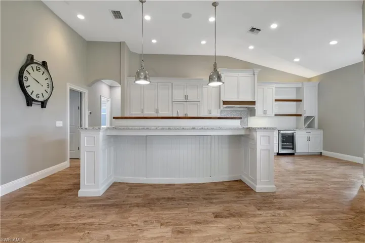 Kitchen with a breakfast bar, decorative light fixtures, white cabinets, a kitchen island, and recessed lighting