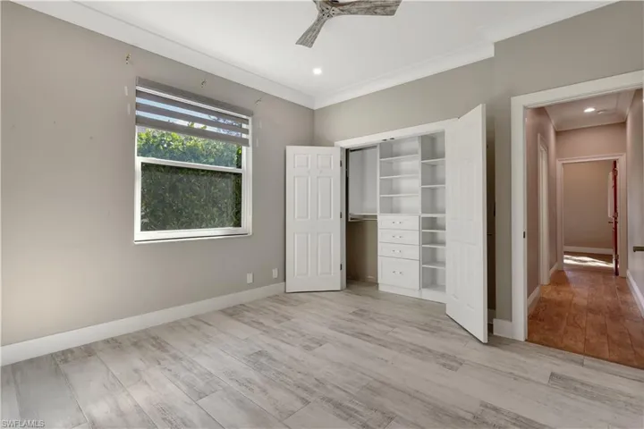 Unfurnished bedroom featuring light wood-type flooring, ornamental molding, a ceiling fan, and a closet