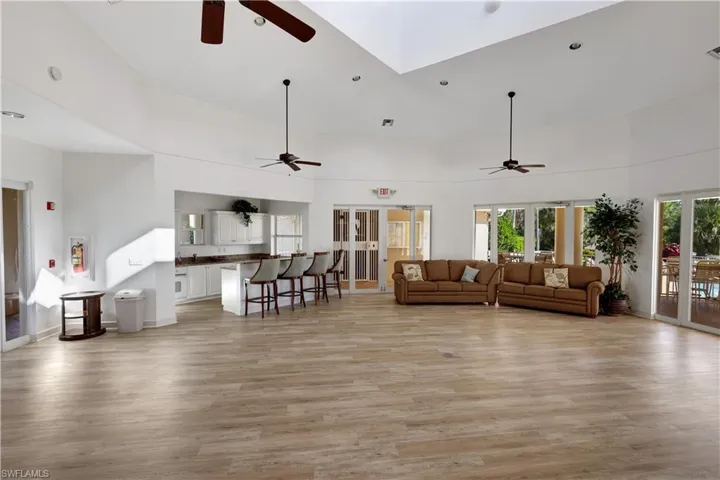 Living room featuring a towering ceiling, light wood-type flooring, and ceiling fan