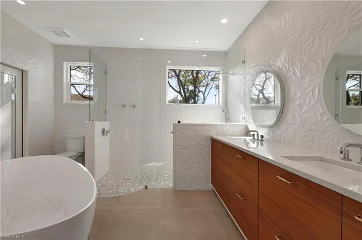 Bathroom with a soaking tub, double vanity, walk in shower, wallpapered walls, and light tile patterned flooring