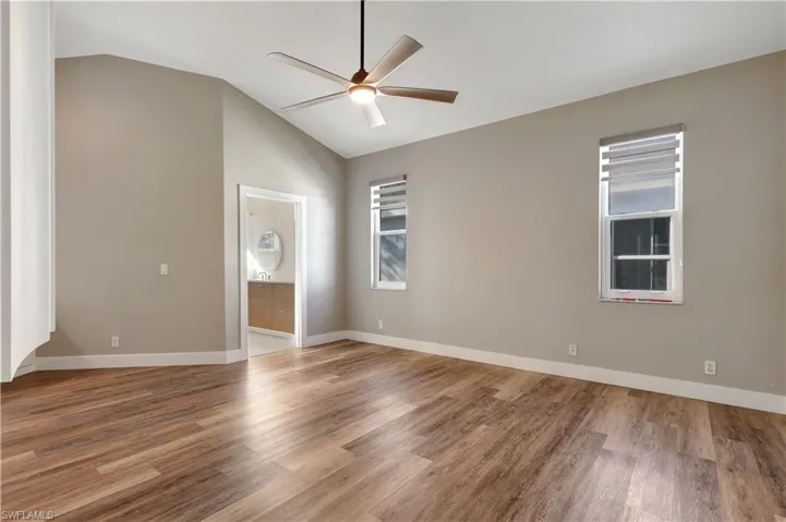 Empty room with light wood-style flooring, lofted ceiling, and ceiling fan