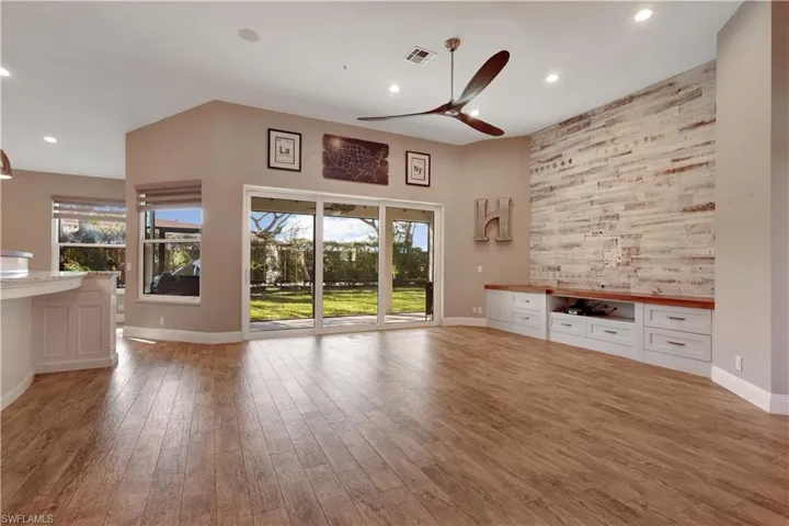 Unfurnished living room featuring ceiling fan, an accent wall, recessed lighting, and light wood finished floors