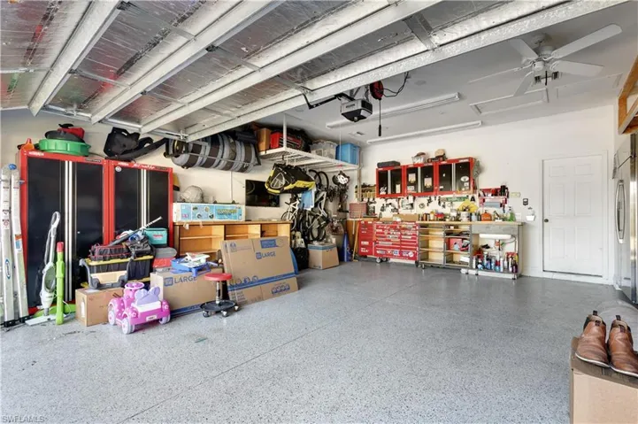 Garage with a workshop area, stainless steel fridge, and a ceiling fan