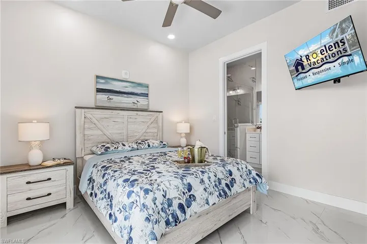 Bedroom with a distressed wood-finish headboard and frame, featuring a ceiling fan, recessed lighting, and large format marble-look floor tiles - Virtually Edited Image