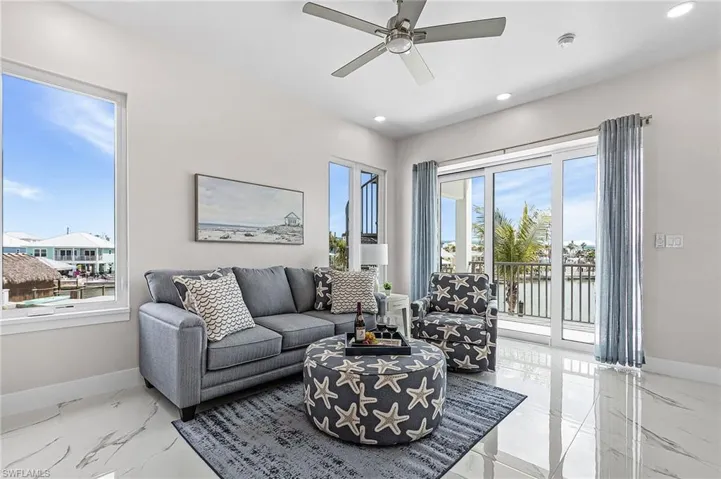 Spacious living area featuring polished tile flooring, recessed lighting, and a ceiling fan - Virtually Edited Image