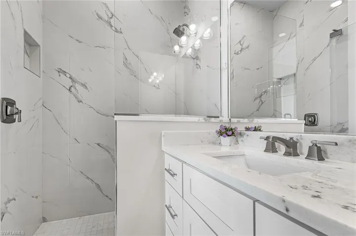 Bathroom featuring a white vanity with an undermount sink, a stone-finish countertop, and a dark bronze faucet - Virtually Edited Image