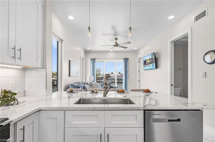 Expansive kitchen island featuring a stainless steel undermount sink, integrated dishwasher, and a light-toned countertop - Virtually Edited Image