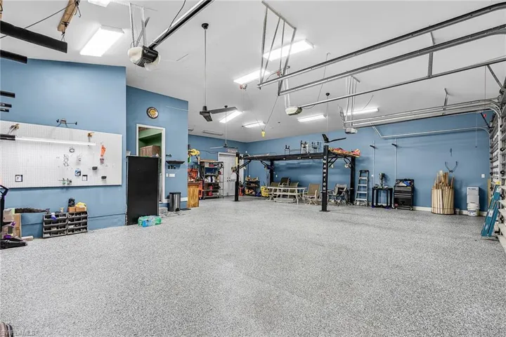 a massive 1,242 sq ft, 5 PLUS car garage, with 3 bay garage doors, comes with a 8,300 lb car lift, epoxy floor, 14’ high ceilings, shop lighting, wired for whole house generator, garage refrigerator, with double exit doors to a fenced back yard