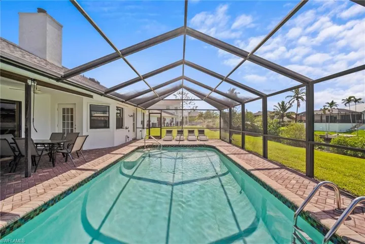 Outdoor pool with ceiling fan, glass enclosure, a yard, and a patio