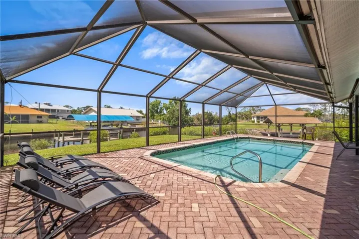 Pool featuring glass enclosure and a patio